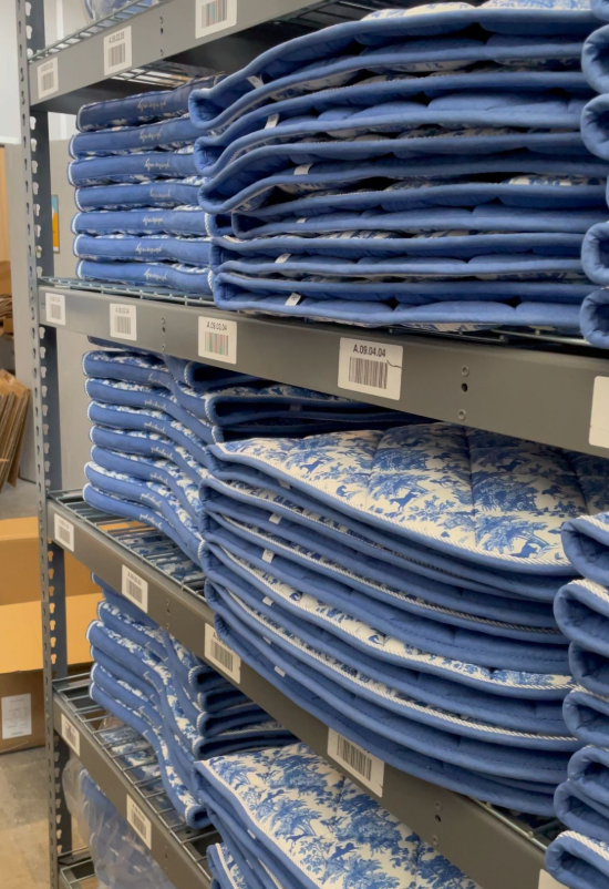 Stacks of blue and white patterned saddle pads on metal shelves in a storage area.